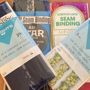 May include: Four packages of stretch lace seam binding in various colors, including navy blue, white with yellow and green accents, and white with yellow accents. The packages are labeled with the brand name "Wrights" and the price "39¢".