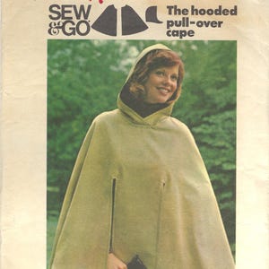 May include: A vintage Butterick 4026 sewing pattern envelope for a hooded pull-over cape, size 12. The cover features a photograph of a light olive green hooded cape with vertical arm slits, labeled with the text Sew & Go and Kasson.