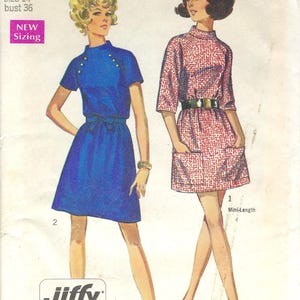 May include: A vintage Simplicity sewing pattern showing two mini-length dresses. One is blue with gold buttons, the other is red and white patterned. The pattern is for Miss size 14, bust 91.4 cm.