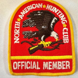 May include: Red and yellow embroidered patch with a white eagle design and the text "North American Hunting Club" and "Official Member".
