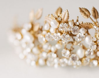 May include: A gold bridal hairpiece with delicate leaves and sparkling crystals and pearls.