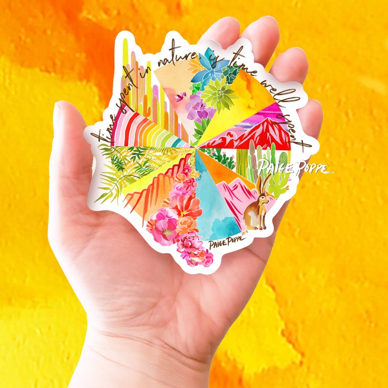 May include: A colorful sticker with a circular design featuring a variety of nature scenes, including cacti, mountains, and flowers. The sticker has the text "Time spent in nature is time well spent" and the artist's signature "Paige Poppe".