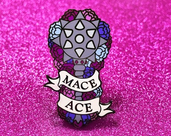 May include: A white enamel pin with a gray mace surrounded by pink, blue, and white flowers. The banner below the mace reads "Mace Ace".