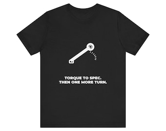 Könnte beinhalten: Ein schwarzes Kurzarm-T-Shirt mit einer weißen Grafik eines Drehmomentschlüssels und dem Text "TORQUE TO SPEC. THEN ONE MORE TURN.", der in weißen Großbuchstaben mittig auf der Brust des Kleidungsstücks gedruckt ist.