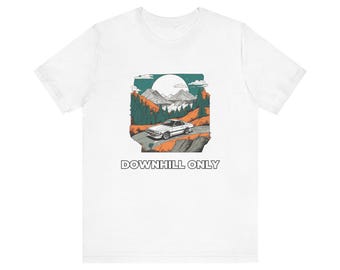 Könnte beinhalten: Ein weißes T-Shirt mit einem Grafikdruck eines weißen Sportwagens auf einer kurvenreichen Straße in einer Berglandschaft mit Kiefern und einem großen Mond. Der Text DOWNHILL ONLY ist in schwarzen Großbuchstaben unter dem Bild gedruckt.