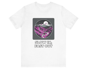 Könnte beinhalten: Ein weißes Kurzarm-T-Shirt mit einem quadratischen Aufdruck, der eine kreisförmige Berglandschaft in Grau-, Weiß- und Magentatönen zeigt. Unter dem Motiv steht der Text SLOW IN, FAST OUT in fetten weißen Buchstaben.