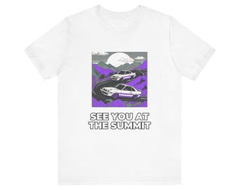 Könnte beinhalten: Ein weißes T-Shirt mit einem Grafikdruck von zwei weißen Autos auf einer kurvenreichen Straße durch violette Berge unter einem großen Mond. Der Text SEE YOU AT THE SUMMIT ist in schwarzen Großbuchstaben unter dem quadratischen Design.