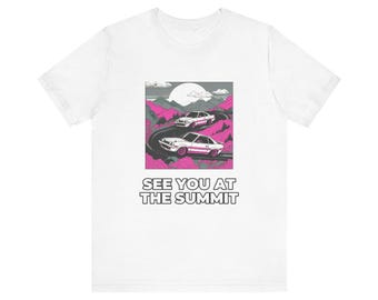 Könnte beinhalten: Ein weißes T-Shirt mit einem Grafikdruck von zwei weißen Sportwagen, die auf einer kurvenreichen Straße durch rosa Berge unter einem großen Mond fahren. Der Text SEE YOU AT THE SUMMIT ist in schwarzen Großbuchstaben unter der Grafik gedruckt.