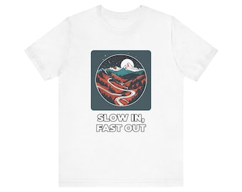 Könnte beinhalten: Ein weißes T-Shirt mit einem Grafikdruck einer kurvenreichen Straße durch Berge unter einem Nachthimmel mit Vollmond. Das Design befindet sich in einem dunkelblauen Quadrat mit dem Text SLOW IN, FAST OUT in weiß unter der Grafik.