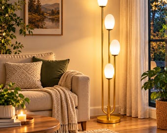 May include: A tall floor lamp with a gold-toned metal frame and four vertical stems of varying heights, each topped with a white, oval-shaped glass globe shade that emits a warm, soft glow in a living room setting.