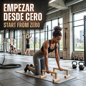May include: A person in a black sports bra and gray leggings performs a push-up exercise on wooden parallettes placed on a mat. The text EMPEZAR DESDE CERO and START FROM ZERO is displayed in the upper left corner of the image.