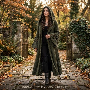 May include: An olive green crochet hooded duster cardigan featuring long, flared sleeves with an intricate openwork pattern, a floor-length hem, and a front-open design worn over a black top and black pants with dark leather boots.