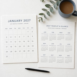 May include: A white 2027 monthly planner page for January and a 2027 year at a glance overview page with dark blue text. The monthly planner features a grid with dates 1 through 31. The year overview displays twelve months.