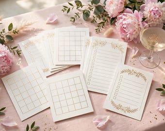 May include: A collection of white paper stationery cards featuring gold foil grid patterns and checklist designs with floral accents. The cards are arranged on a light pink surface alongside pink peony flowers and a glass of champagne.