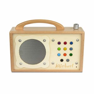 Peut inclure: Un lecteur audio rectangulaire en bois avec un cadre en bois clair et une poignée supérieure. Le panneau avant présente une grille de haut-parleur circulaire argentée et une grille de douze boutons colorés. Le mot "hörbert" est imprimé en brun.