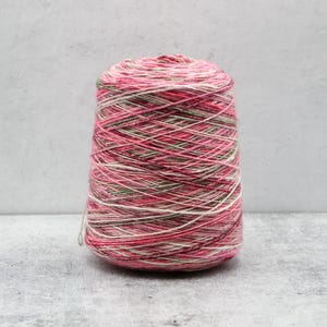 May include: A conical spool of yarn featuring a variegated color palette of vibrant pink, soft white, and muted sage green. The thread is wound tightly in a crisscross pattern around the central core, creating a textured and multi-tonal appearance.