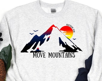 May include: A white sweatshirt with a graphic of a mountain range with a sunset and the text "Matthew 17:20 MOVE MOUNTAINS".