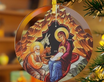以下が含まれることがあります： 宗教的なシーンが描かれた丸いクリスマスオーナメント。オーナメントには、マリアが幼いイエスを抱き、ヨセフと動物たちが描かれた降誕の様子が描かれています。オーナメントは透明で、吊り下げ用の金色のリボンが付いています。