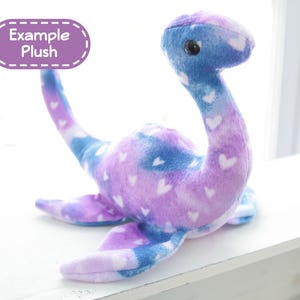 K&ouml;nnte beinhalten: Ein Pl&uuml;schtier in Form eines Seeungeheuers, in Blau, Lila und Wei&szlig; mit Herzmustern. Das Spielzeug hat einen langen Hals, Flossen und ein kleines, rundes Auge. Der Text "Example Plush" befindet sich in einem lila Oval.