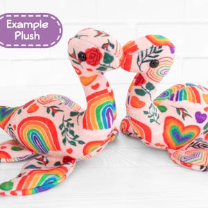 K&ouml;nnte beinhalten: Zwei Pl&uuml;schtierkreaturen mit langen H&auml;lsen und flossenartigen Anh&auml;ngseln. Die Spielzeuge sind mit einem rosa Stoff mit einem Muster aus Regenbogen, Herzen und floralen Elementen bedeckt. Der Text "Example Plush" befindet sich in einem lila Oval.
