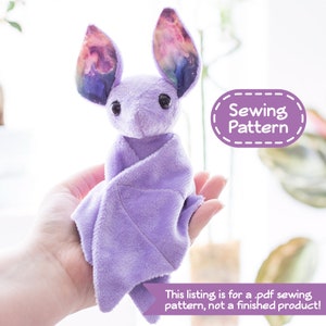 A photo of a small purple bat plush sitting in a person's hand. Overlaying the image are text bubbles reading "Sewing Pattern" and "This listing is for a .pdf sewing pattern, not a finished product!"