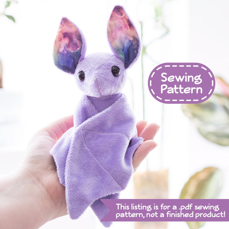 A photo of a small purple bat plush sitting in a person's hand. Overlaying the image are text bubbles reading "Sewing Pattern" and "This listing is for a .pdf sewing pattern, not a finished product!"