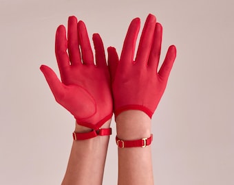 May include: A pair of red mesh gloves with gold accents on the wrist straps. The gloves are held up with the palms facing outward.