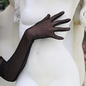 May include: A pair of black sheer long gloves with a delicate texture. The gloves are worn on a white statue of a woman.