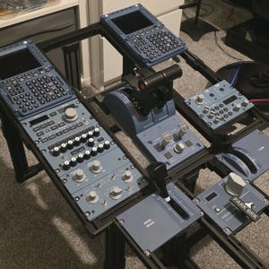 May include: A flight simulator cockpit control panel set featuring blue modules with various knobs, switches, and digital displays. The setup includes a throttle quadrant, speed brake lever, and a parking brake labeled PARK BRK.