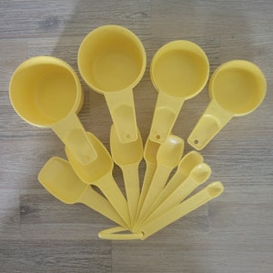 May include: A set of yellow measuring cups and spoons. The set includes 1/4 cup, 1/3 cup, 1/2 cup, 1 cup, 1 teaspoon, 1/2 teaspoon, 1/4 teaspoon, and 1/8 teaspoon.