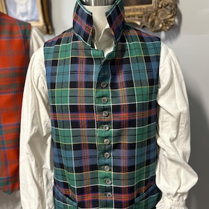 May include: A green, blue, and black plaid vest with a high collar and button-down front. The vest is paired with a white long-sleeved shirt with ruffled cuffs. A second vest with a red and orange plaid pattern is partially visible in the background.