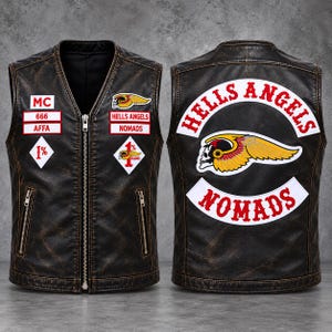May include: A dark brown distressed leather vest featuring a front zipper, two zippered pockets, and various patches including MC, 666, AFFA, and 1%. The back displays large Hells Angels Nomads text and a winged skull graphic patch.