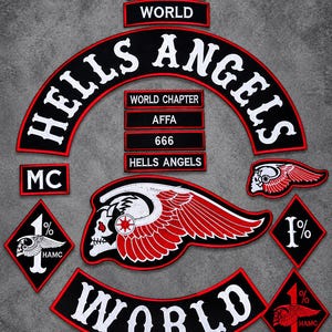May include: A collection of embroidered patches featuring black fabric with red borders and white text. The set includes a large arched Hells Angels patch, a World rocker, a winged skull emblem, and diamond-shaped 1% patches with text including Nomads, World Chapter, AFFA, 666, and HAMC.