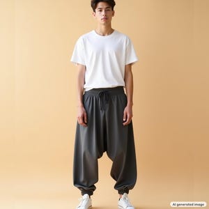 May include: A plain white short-sleeved crew neck t-shirt paired with loose-fitting dark gray drop-crotch trousers featuring an elastic waistband with a drawstring tie and cuffed ankles, worn with simple white sneakers.