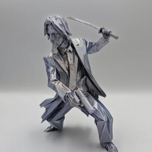 Könnte beinhalten: Eine metallisch silberfarbene Figur, die eine Person in Anzug und Krawatte in einer dynamischen Action-Pose darstellt. Die Figur hält ein Schwert in der einen und eine Pistole in der anderen Hand, mit scharfen, kantigen, geometrischen Facetten.