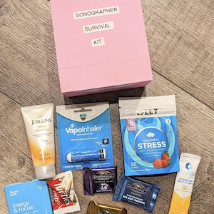 May include: A pink gift bag labeled Sonographer Survival Kit containing various items: a tube of Jergens Ultra Healing lotion, a VapoInhaler, a pouch of Olly Goodbye Stress gummies, a pack of Neuro gum, Turtles bites, and three Ghirardelli chocolate squares.