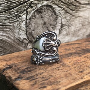 May include: A silver spoon ring with an ornate design. The ring is made from a vintage spoon and has a unique, handcrafted look.