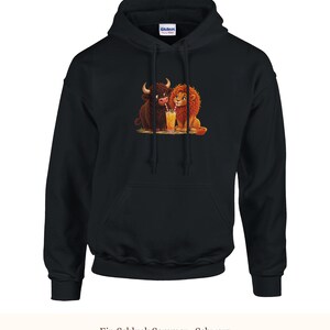 K&ouml;nnte beinhalten: Ein schwarzer Kapuzenpullover mit einem Grafikdruck eines braunen Bisons und eines L&ouml;wen, die zusammensitzen und sich ein hohes Glas Orangensaft mit zwei Strohhalmen teilen. Das Kleidungsst&uuml;ck hat eine Kapuze mit Kordelzug und eine K&auml;ngurutasche.