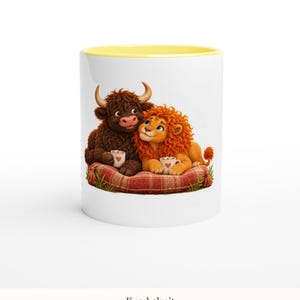 May include: A white ceramic mug with a yellow rim featuring a graphic of a brown Highland cow and an orange lion sitting on a red plaid cushion, each holding a small white mug with a red heart design, set against a plain white background.