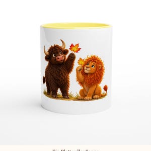 May include: A white ceramic mug with a yellow interior rim featuring a cartoon illustration of a brown highland cow and an orange lion, each holding a vibrant autumn maple leaf. The text "Ein Blatt voller Sonne" is printed below the image.