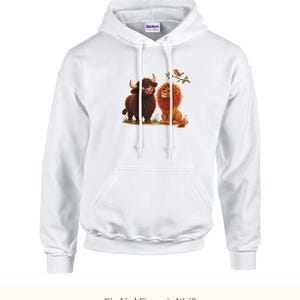 K&ouml;nnte beinhalten: Ein wei&szlig;er Kapuzenpullover mit einem Grafikdruck, der ein braunes Hochlandrind und einen goldenen L&ouml;wen zeigt, die zusammen auf Gras sitzen, mit einem kleinen Vogel auf einem Ast dar&uuml;ber. Der Hoodie hat lange &Auml;rmel und eine K&auml;ngurutasche.