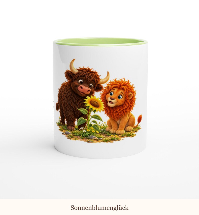 May include: A white ceramic mug with a light green interior rim featuring a colorful illustration of a brown highland cow and an orange lion sitting together next to a yellow sunflower. The text Sonnenblumengl&uuml;ck is printed below.