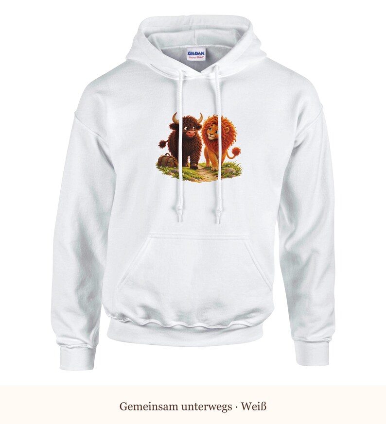 K&ouml;nnte beinhalten: Ein wei&szlig;er Kapuzenpullover mit einem Grafikdruck, der ein braunes Hochlandrind und einen goldenen L&ouml;wen zeigt, die zusammen auf einer gr&uuml;nen Grasfl&auml;che stehen. Der Hoodie hat eine K&auml;ngurutasche, lange &Auml;rmel und wei&szlig;e Kordelz&uuml;ge.