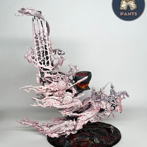 Puede incluir: Una figura de juego en miniatura con una estructura alta y compleja en rosa pálido y blanco, que incluye figuras esqueléticas, un caldero negro con líquido rojo y jinetes sobre una base circular oscura y texturizada. Logo TROLL PANTS.