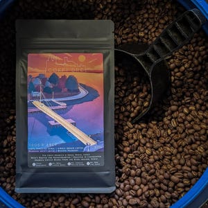 May include: A matte black coffee bag with a colourful label featuring a pier illustration and the text COFFI DRE DROS R ABER. The label includes the weight 225g and details about the single origin coffee beans from the Nyeri region, Kenya.