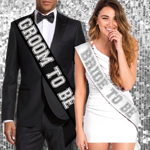 May include: A black and white sash with the text "Groom to Be" and a white sash with the text "Bride to Be".