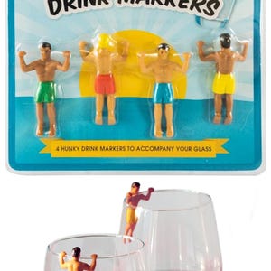 Puede incluir: Marcadores de bebidas con figuras en trajes de ba&ntilde;o coloridos. El empaque dice "Hunks in Trunks Drink Markers" y "4 Hunky Drink Markers to Accompany Your Glass". Los marcadores se muestran en copas de vino.
