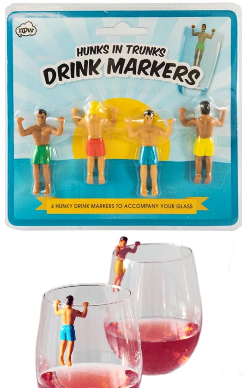 Puede incluir: Marcadores de bebidas con figuras en trajes de ba&ntilde;o coloridos. El empaque dice "Hunks in Trunks Drink Markers" y "4 Hunky Drink Markers to Accompany Your Glass". Los marcadores se muestran en copas de vino.