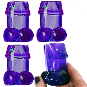 May include: Four purple shot glasses shaped like a male anatomy. The glasses are made of plastic and have a smooth, shiny finish.