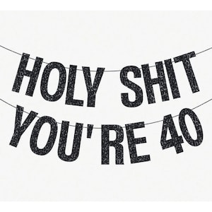 May include: A banner with the text "HOLY SHIT YOU'RE 40" in black glitter letters, strung on a thin black string, against a white background. The banner is designed for a 40th birthday celebration.